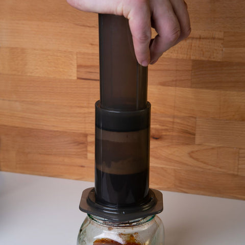 hand pushing down coffee through an aeropress coffee maker