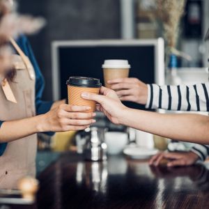 a barista handing coffee to customers in a coffee shop