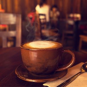 a brown mug of maple syrup coffee on a table in a coffee shop with people in the background