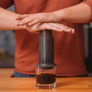 close-up view of a man pushing down on an aeropress coffee maker