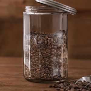 a clear jar half-full of whole roasted coffee beans